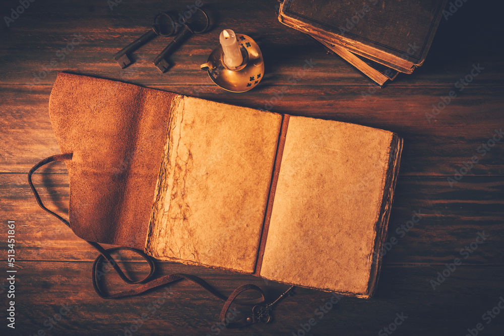 Blank antique leather-bound journal, book or diary with old books and candle