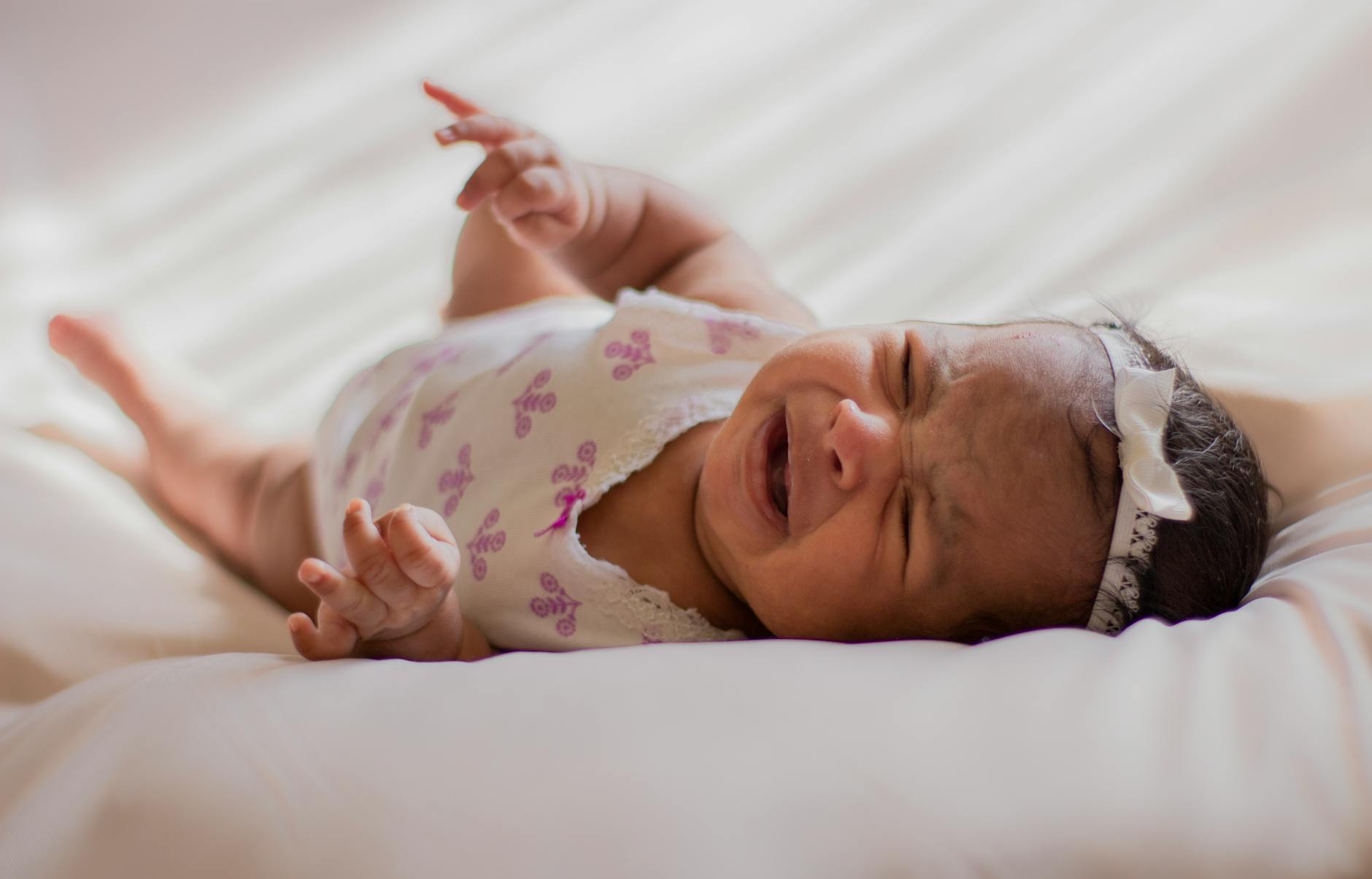baby in a onesie lying on bed