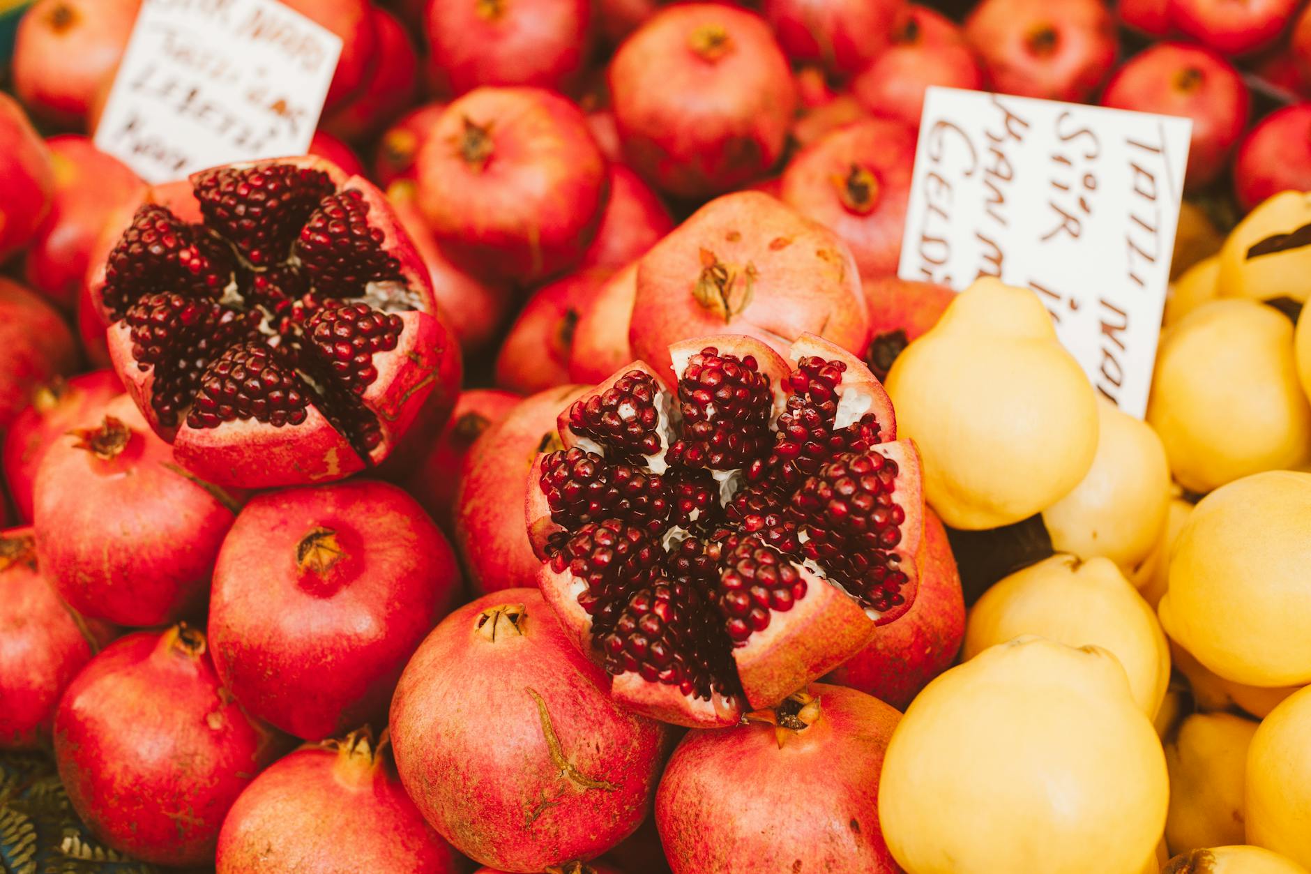 close up photograph of red pomegranates beside yellow quinces