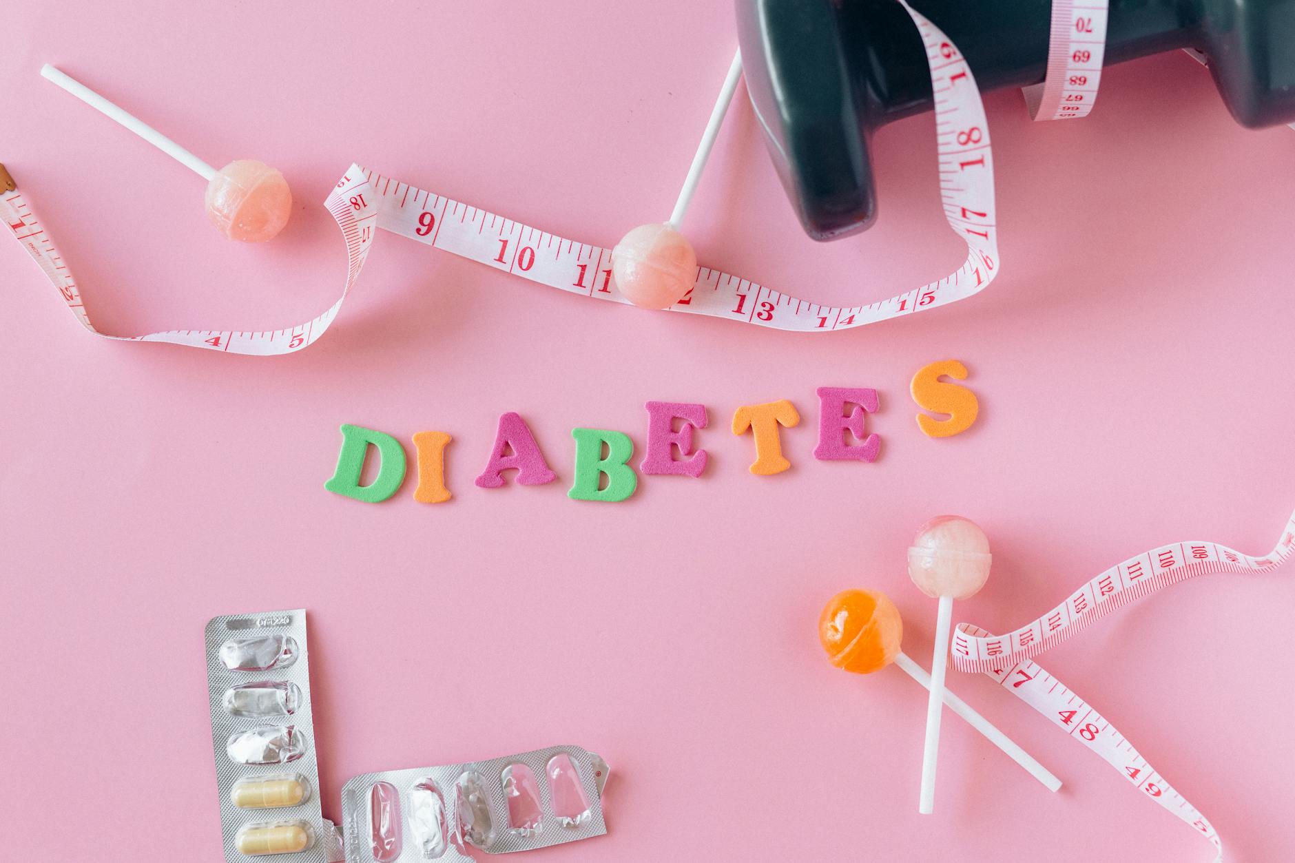 lollipops meter and medicaments on a pink background around letters creating a word diabetes